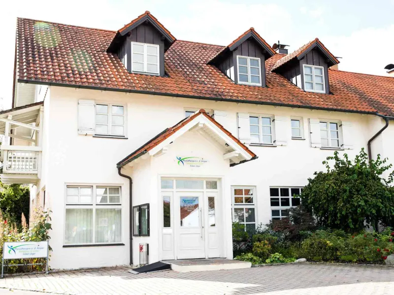 Das weiße Praxisgebäude mit rotem Dach und Praxisschild