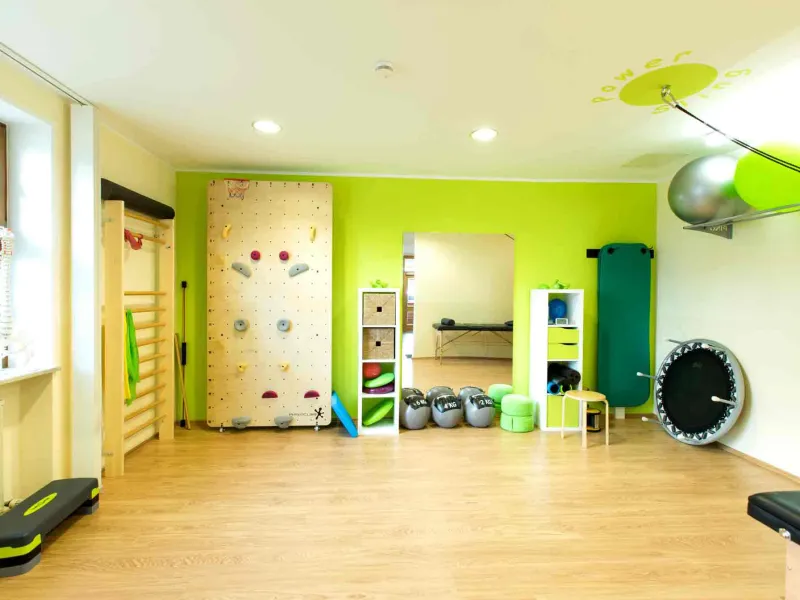 Trainingsraum der Praxis mit grüner Wand, Kletterwand und Sprossenwand